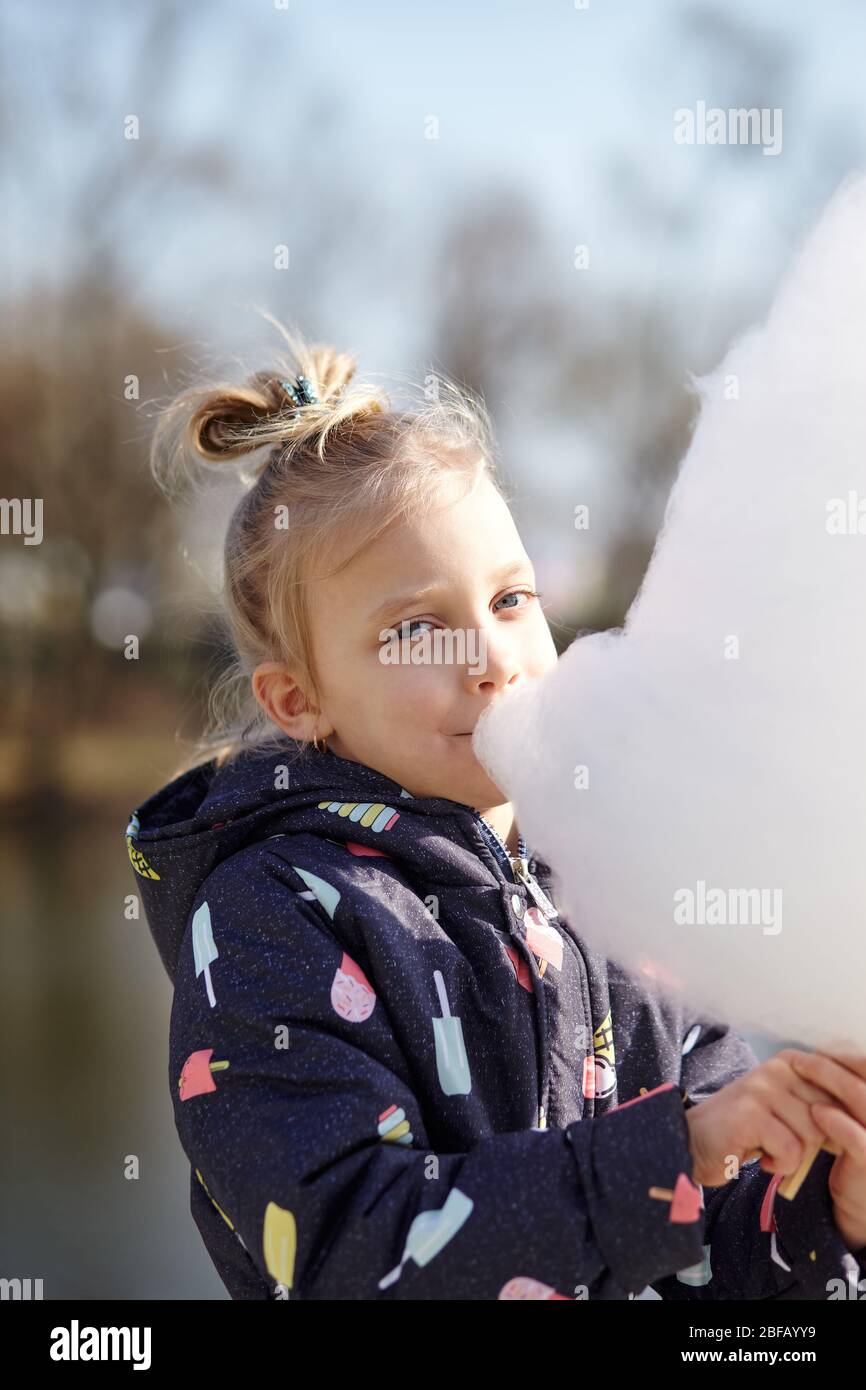 Nettes kleines Mädchen essen Zuckerwatte. Glückliche Kindheit und Kinder Emotionen Stockfoto