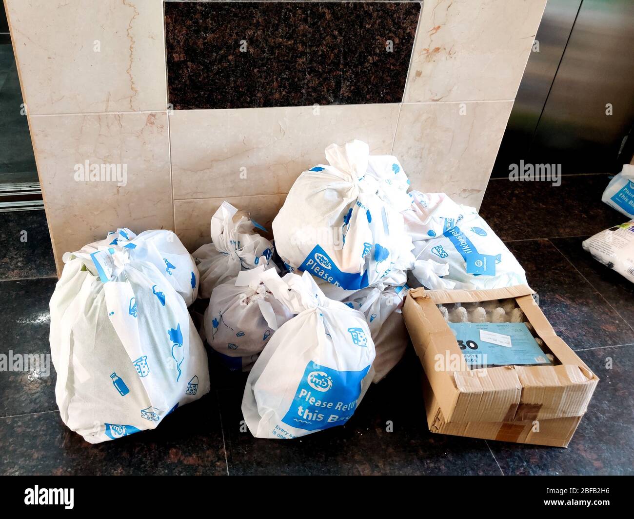 Weiße Beutel mit Milchkorb auf ihnen in der Nähe eines Lifts als Teil der Lieferung in der Wohnung platziert Stockfoto