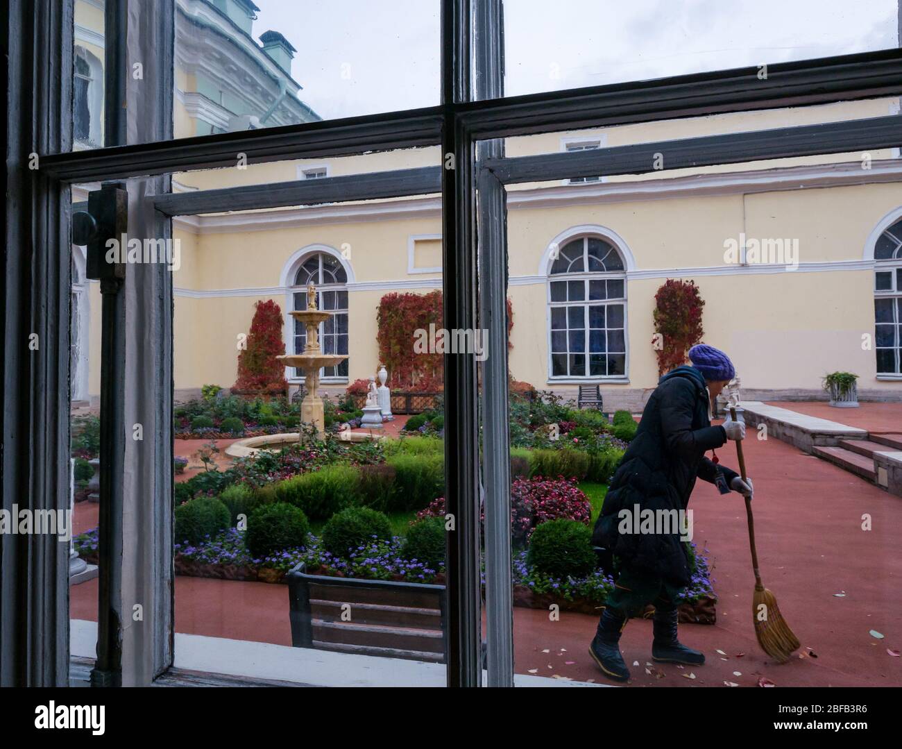Blick auf den formellen Innenhof mit Frau fegenden Blättern, Eremitage State Museum, Winterpalast, St. Petersburg, Russische Föderation Stockfoto