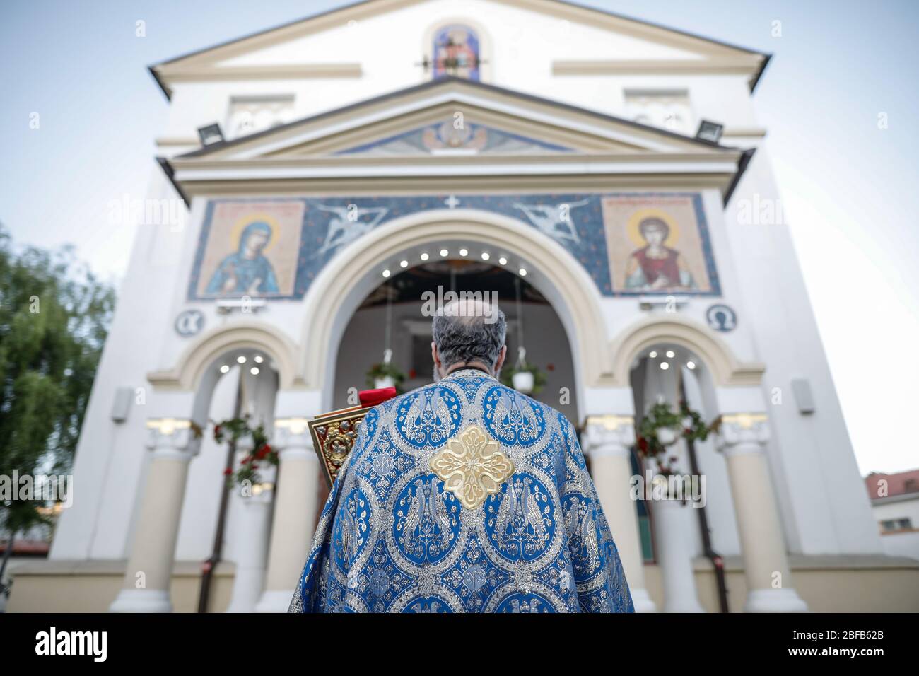 Geringe Schärfentiefe (selektiver Fokus) Details mit einem rumänischen orthodoxen christlichen Priester, der eine Heilige Bibel vor einer Kirche hält. Stockfoto