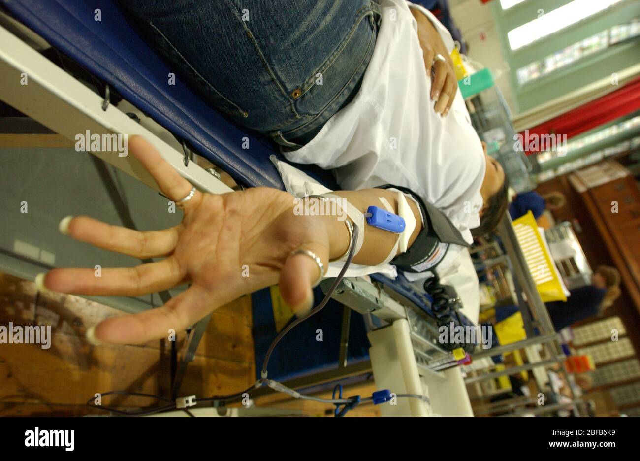 Junge Frau Spender mit offenen Faust als Blut fließt durch die Nadel und das Rohr in einer Aufbewahrungstasche. Stockfoto