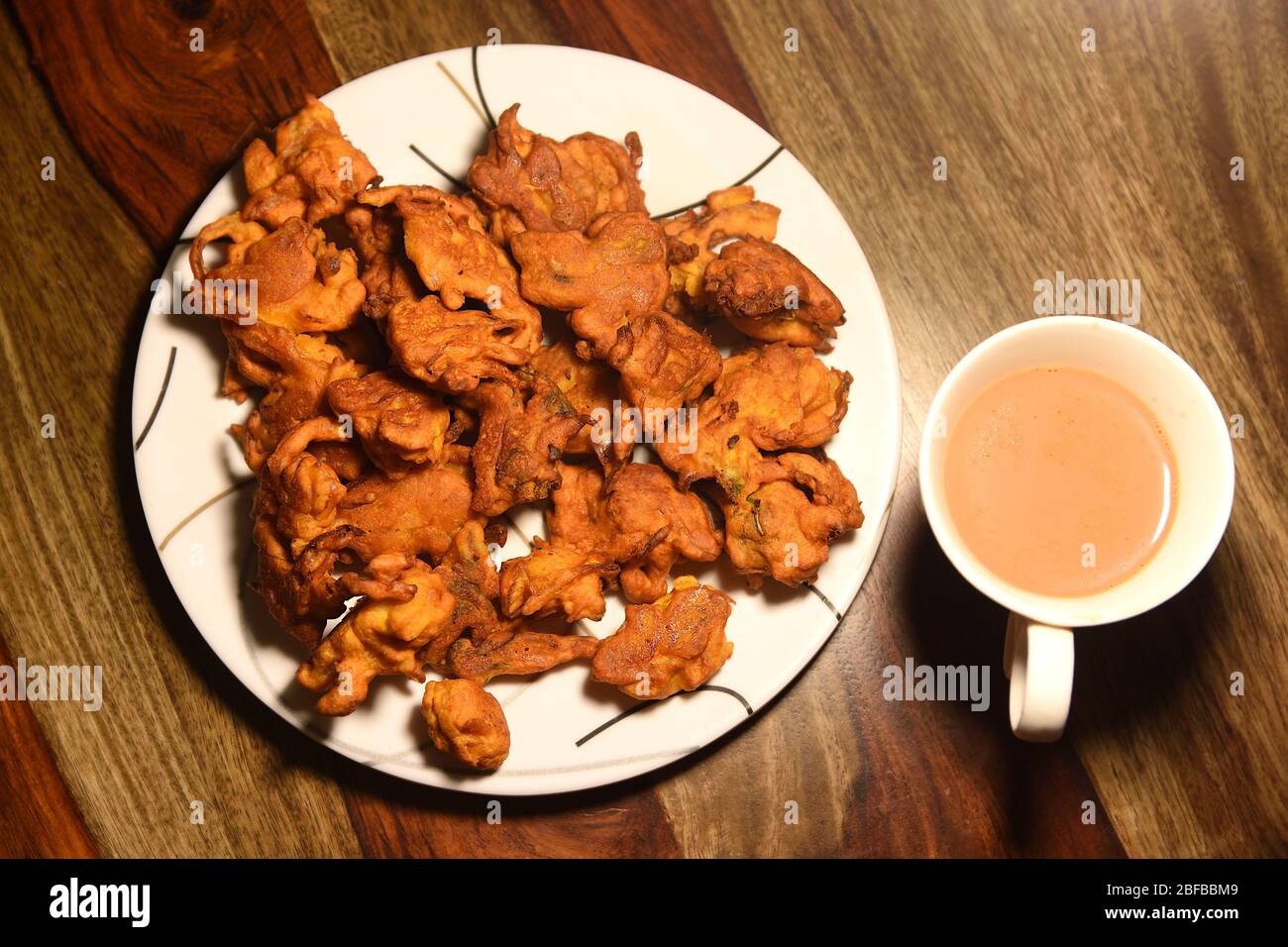 Chai mit Pakoras und Bhajiyas und serviert auf Teller auf Holzhintergrund Stockfoto