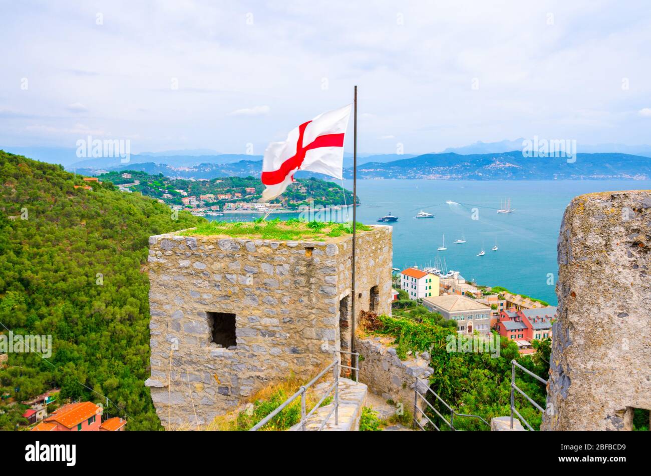 Top Luftaufnahme des Golfs von Spezia türkisfarbenes Wasser, alte Steinmauer von Castello Doria Burgturm mit Flagge in Portovenere Stadt, Ligurisches Meer, Rivi Stockfoto