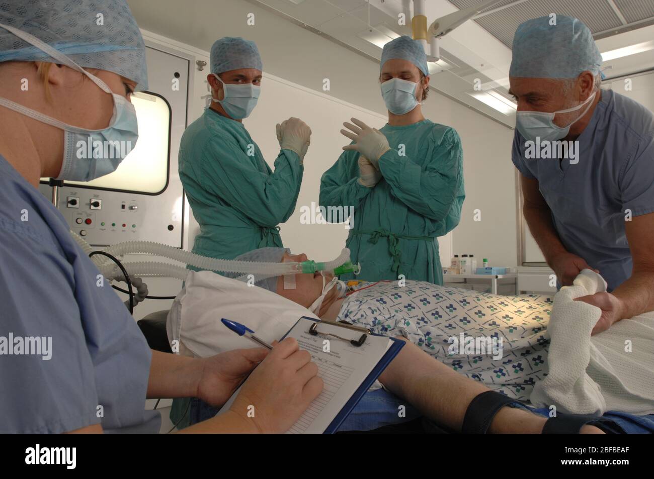 Eine Patientin, die auf einem Rollbett in einem Operationssaal liegt, vollständig für den Eingriff vorbereitet, betäubt und eine Sauerstoffmaske trägt. Im Bac Stockfoto