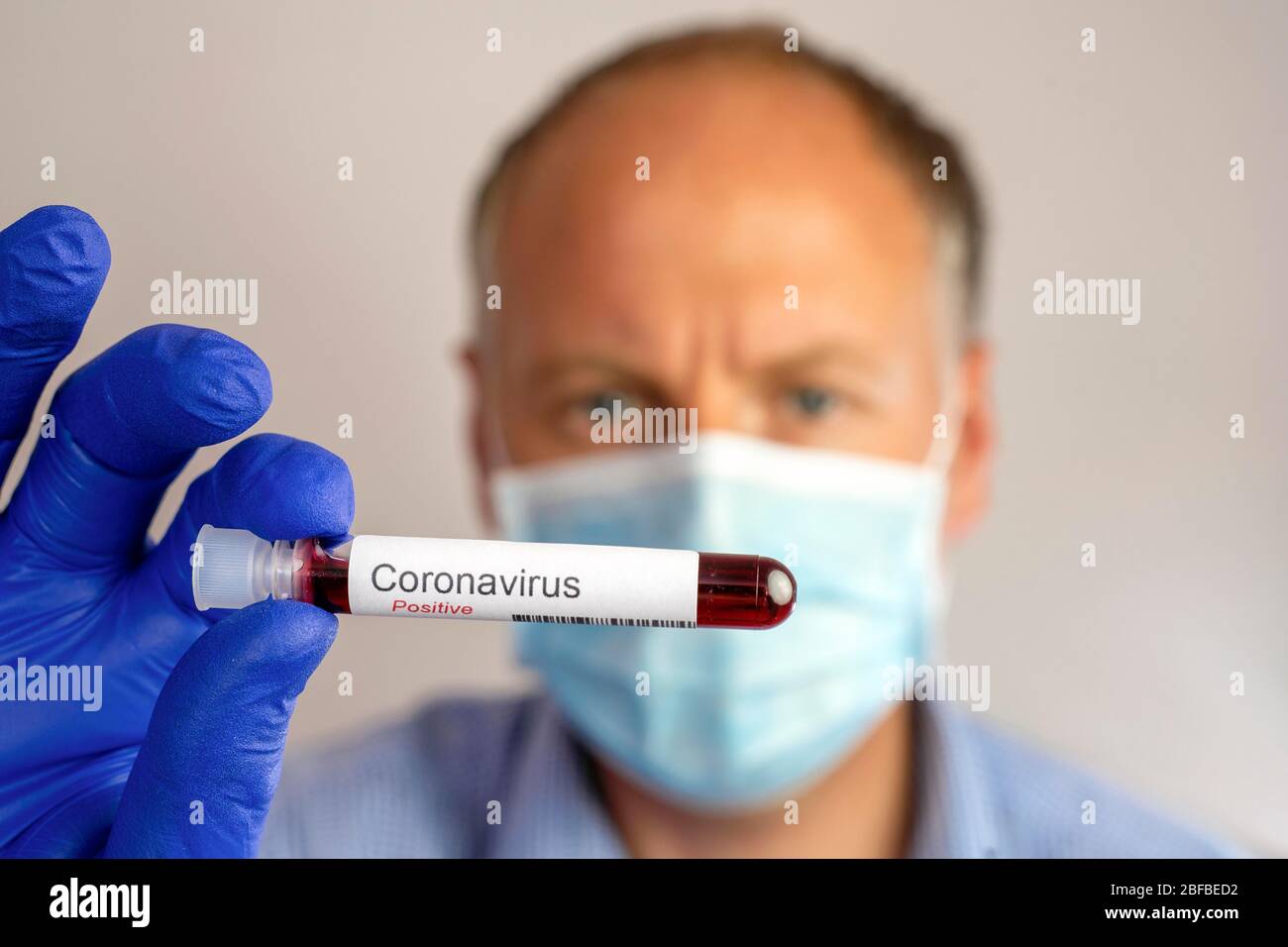 Mann mit Schutzmaske und positivem Ergebnis seines Coronavirus-Tests, Deutschland Stockfoto