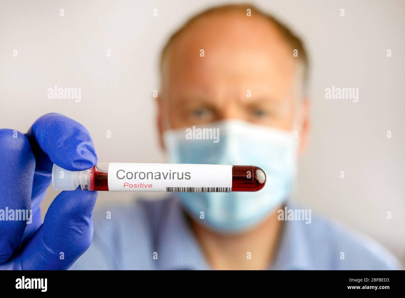 Mann mit Schutzmaske und positivem Ergebnis des Coronavirus-Tests, Deutschland Stockfoto