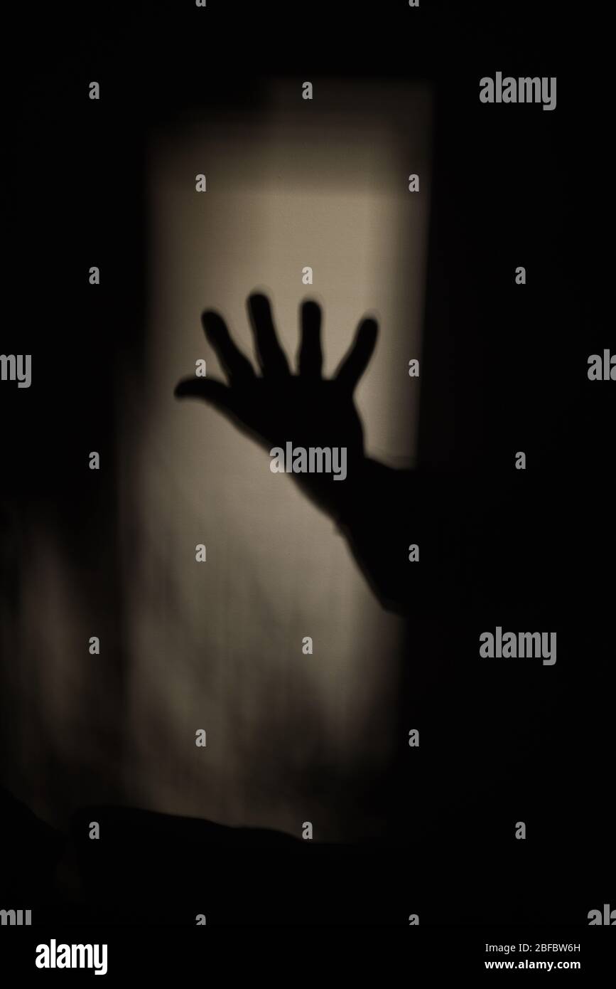 Der Schatten einer offenen Hand zeigt sich im Licht einer dunklen Wand Stockfoto