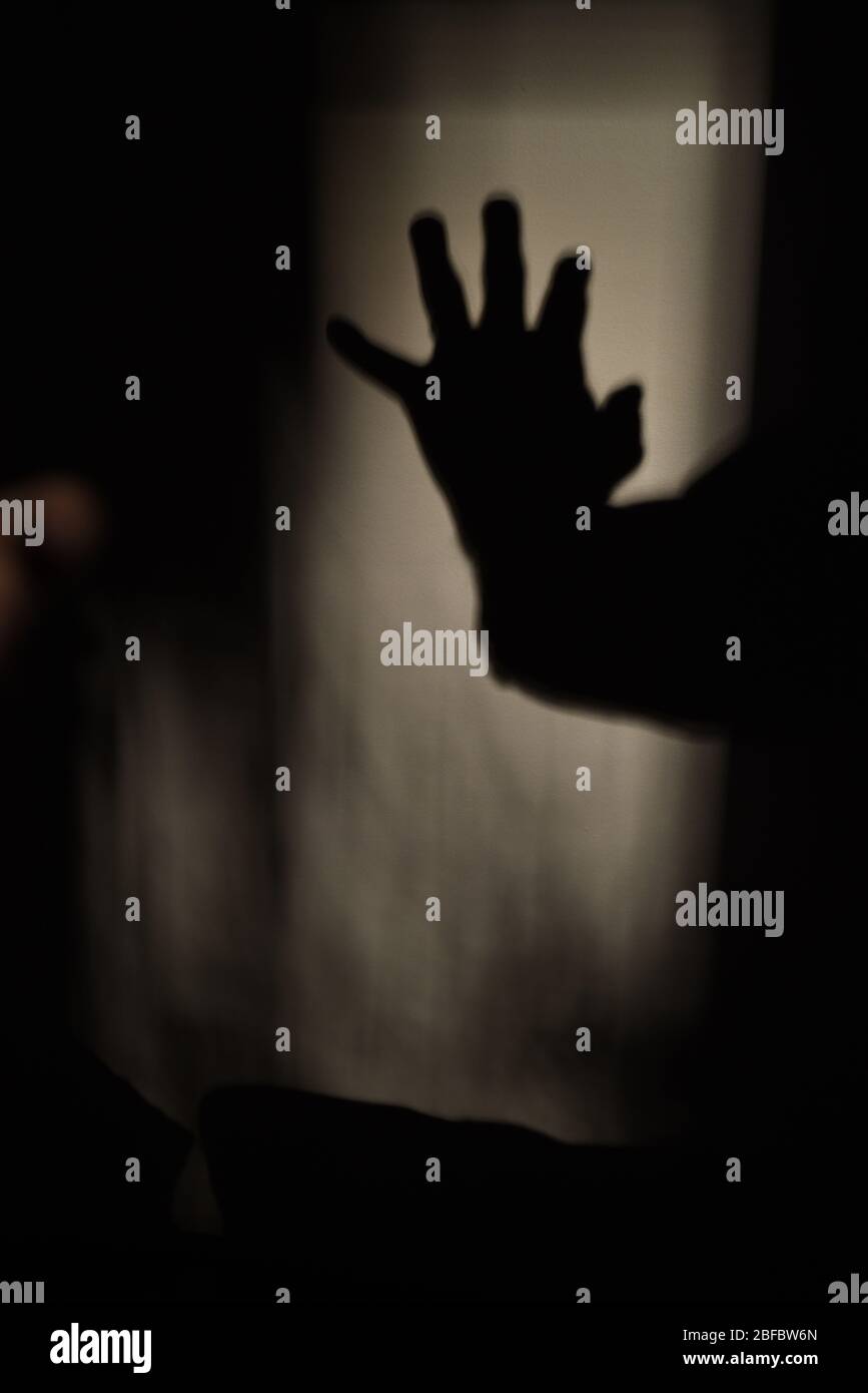 Der Schatten einer offenen Hand zeigt sich im Licht einer dunklen Wand Stockfoto