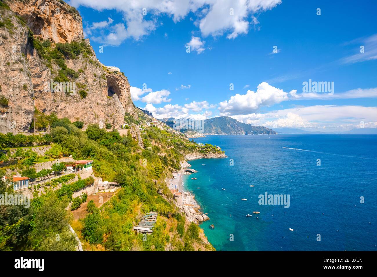 Die Amalfiküste in der Nähe von Positano und Sorrento an einem Sommernachmittag mit Booten im Wasser, einem Sandstrand und Häusern und Resorts am Hang Stockfoto