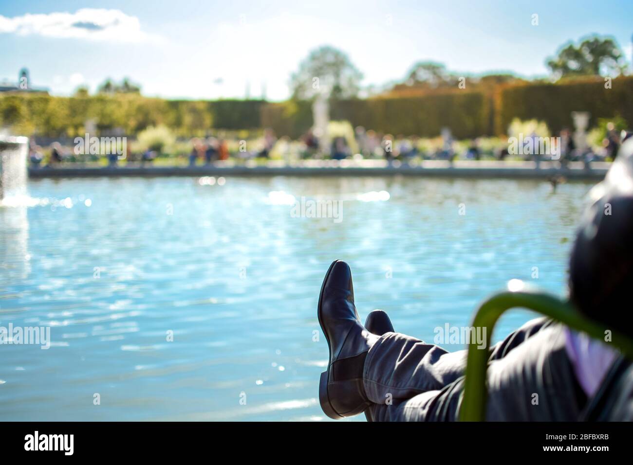 Ein Pariser Mann entspannt mit seiner Füße auf dem Gran Bassin Rond Brunnen in den Tuilerien in Paris Frankreich in Earlly Herbst Stockfoto