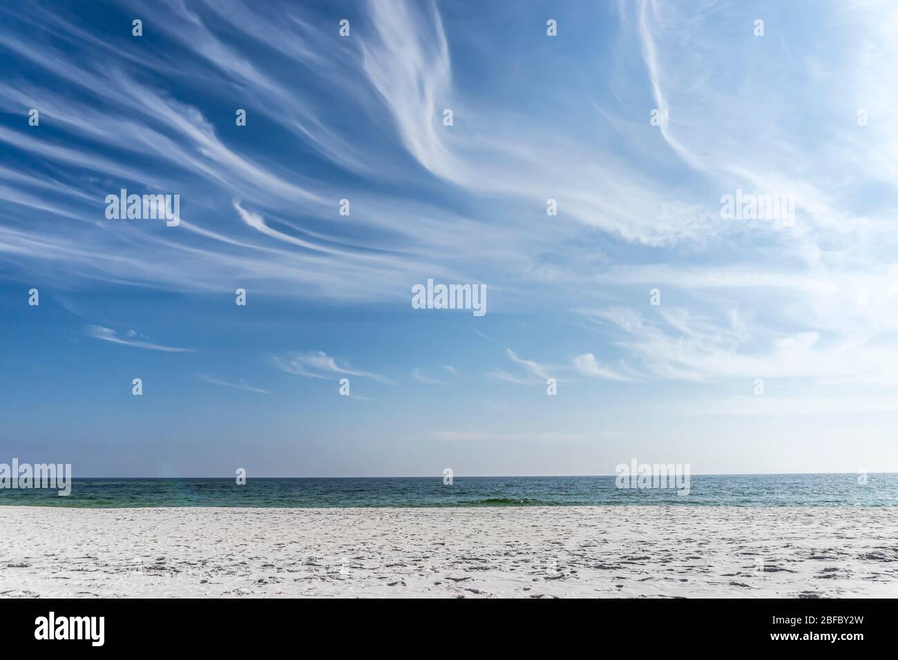 Der weiße Sandstrand von Pensacola, Florida, kontrastiert mit dem tieftürkisfarbenen Meer und dem blauen Himmel, der mit wisigen Zirruswolken gefüllt ist Stockfoto