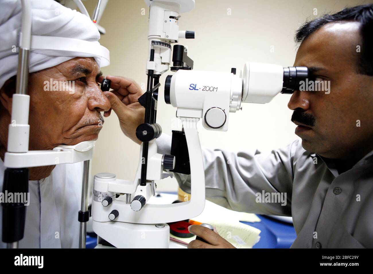 Ein Augenarzt untersucht und ältere Männer Augen mit einer Spaltlampe. Es ist in der Lage, einen feinen Lichtstrahl in das Auge des Patienten und Magnifie zu leuchten Stockfoto