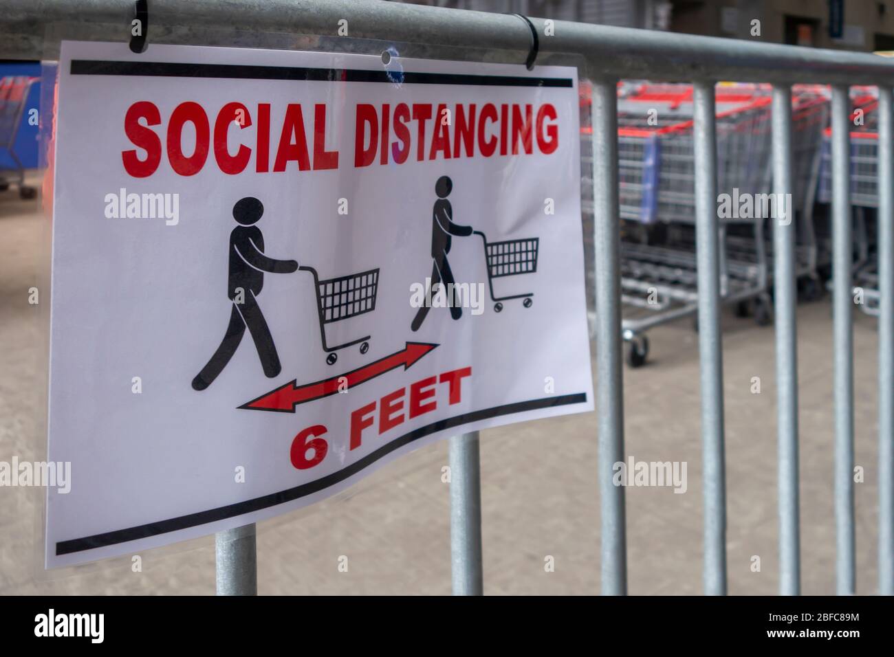 Weiße schwarz-rote soziale Distanzierung Posting für Coutomers, die einen Shooping Dtore mit Einkaufswagen unterhalten Stockfoto