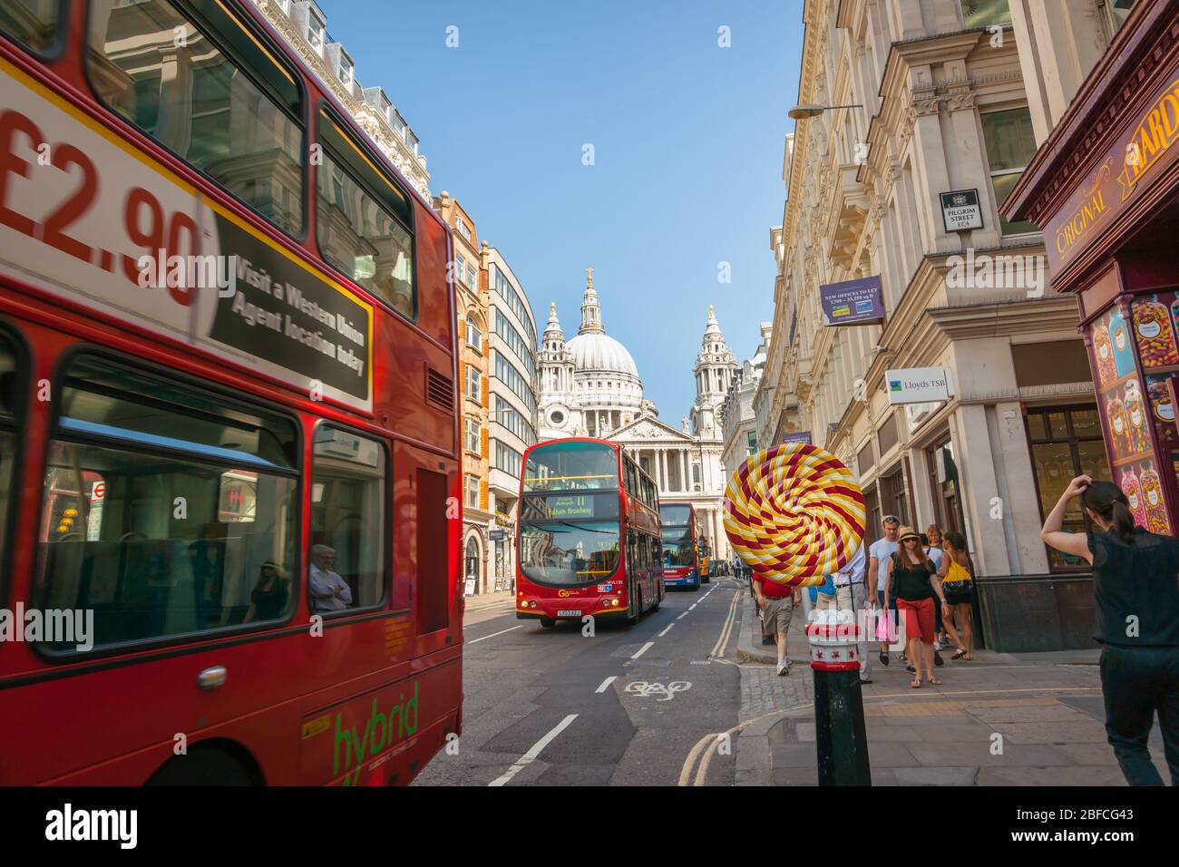London England - Juli 19 2013; Londoner Straßenszene mit Doppeldeckerbussen, die an einem riesigen Lollypop vorbeifahren, während die Leute vorbeilaufen. Stockfoto