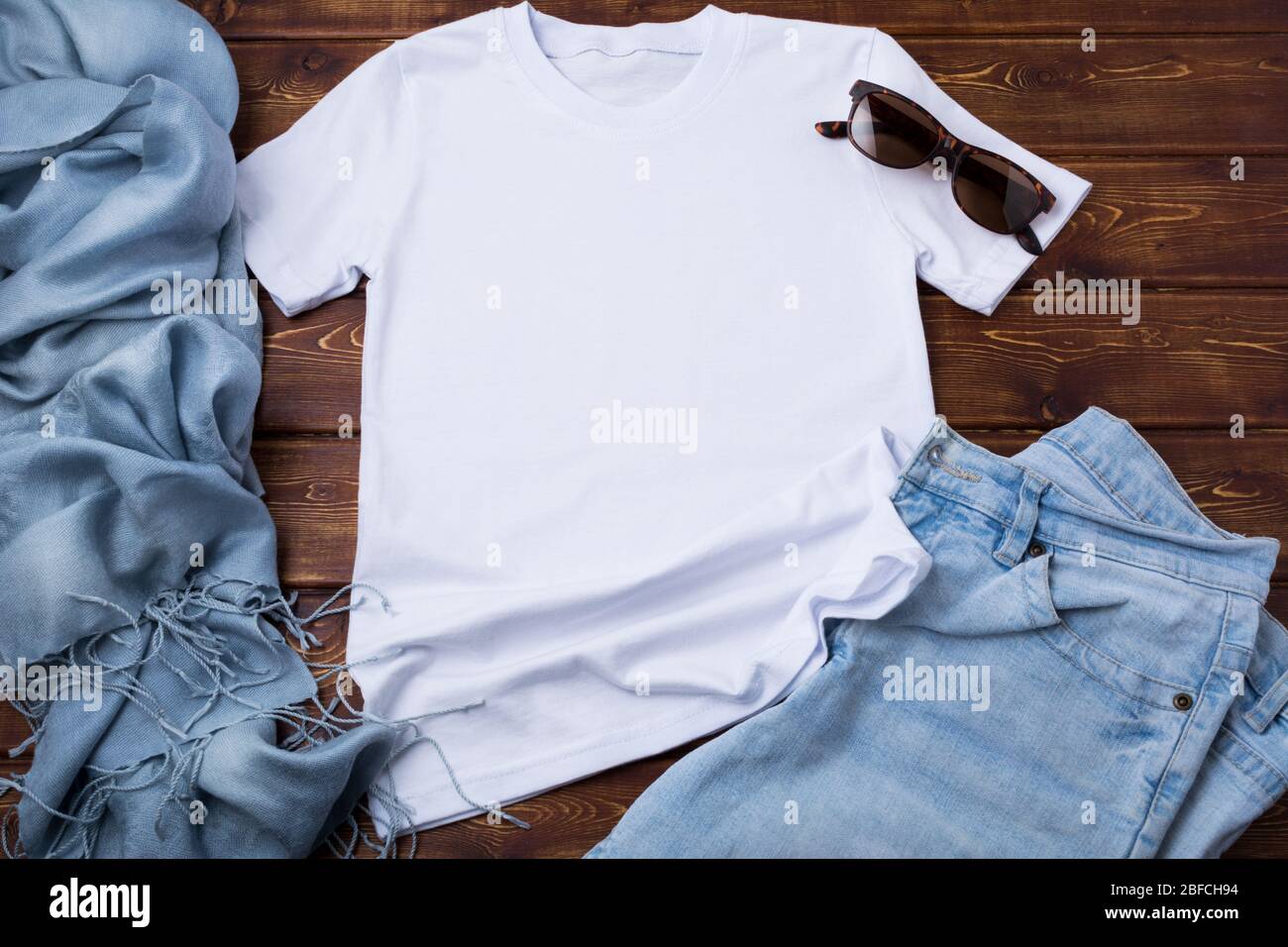 Weißes Damen-T-Shirt aus Baumwolle mit blauen Jeans, Sonnenbrille und türkisfarbenem Schal. Design T-Shirt Vorlage, T-Print Präsentation Mock up Stockfoto