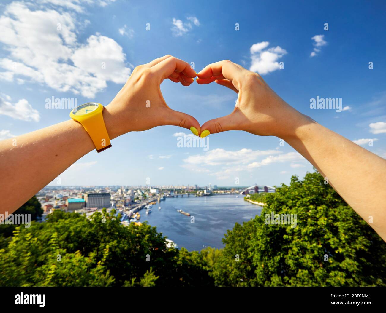 Frau Hände in Form von Herzen mit gelben Hut gegen Panorama der Innenstadt von Kiew in der Ukraine Stockfoto