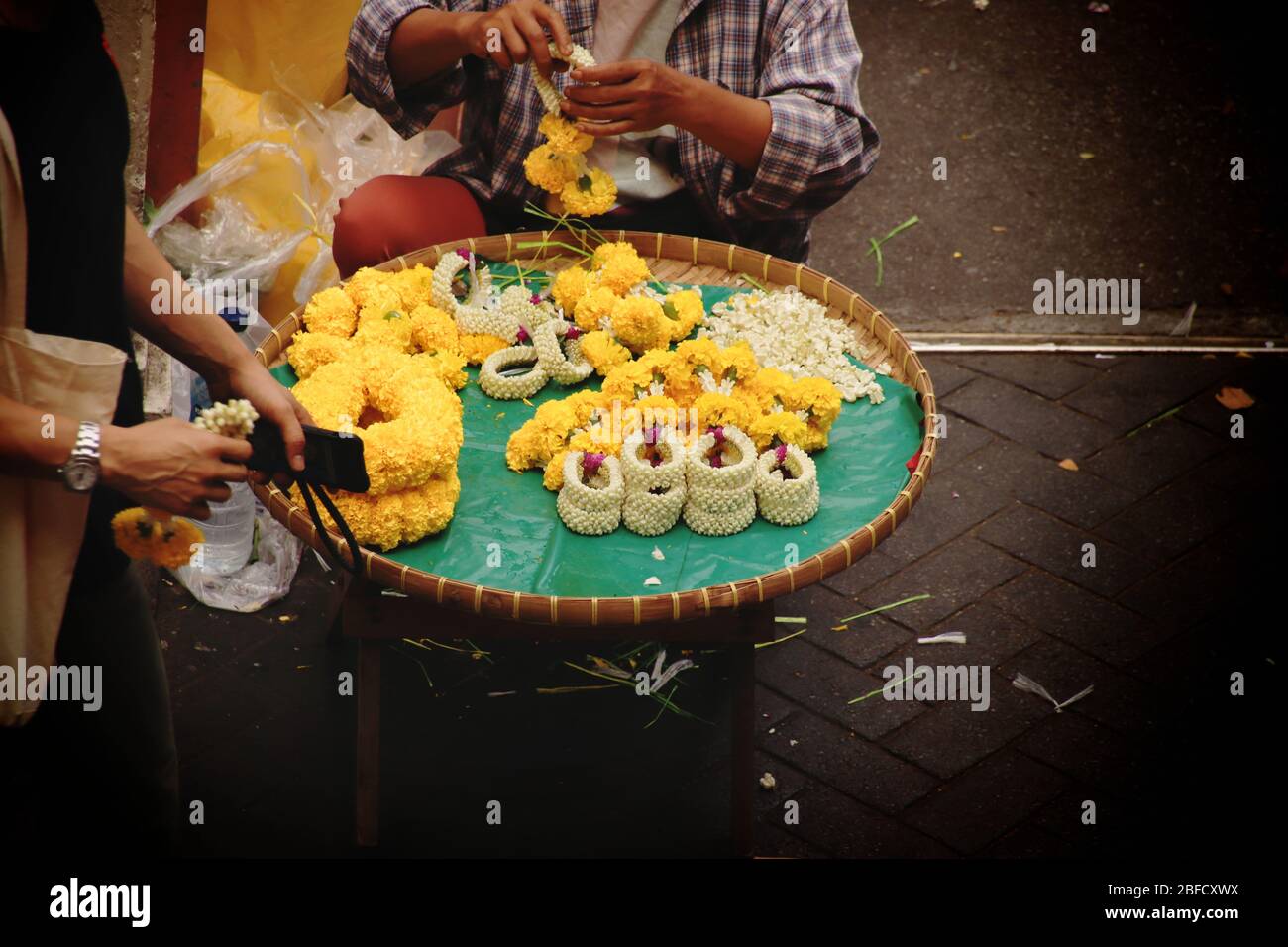Thailändischer Straßenverkäufer, der Phuang malai oder malai verkauft, eine Blumengirlande, die für buddhistische Opfergaben und Glücksbringer in der thailändischen Kultur verwendet wird Stockfoto