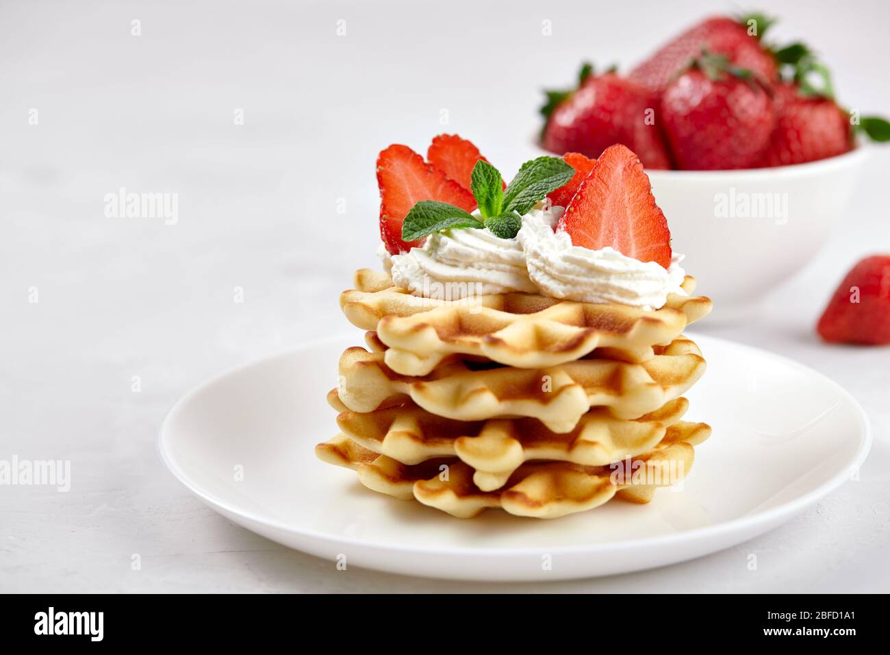 Wunderschönes Frühstück. Hausgemachte belgische Wiener Waffeln mit Erdbeeren, Tee auf einem hellen Hintergrund dekoriert. Stockfoto