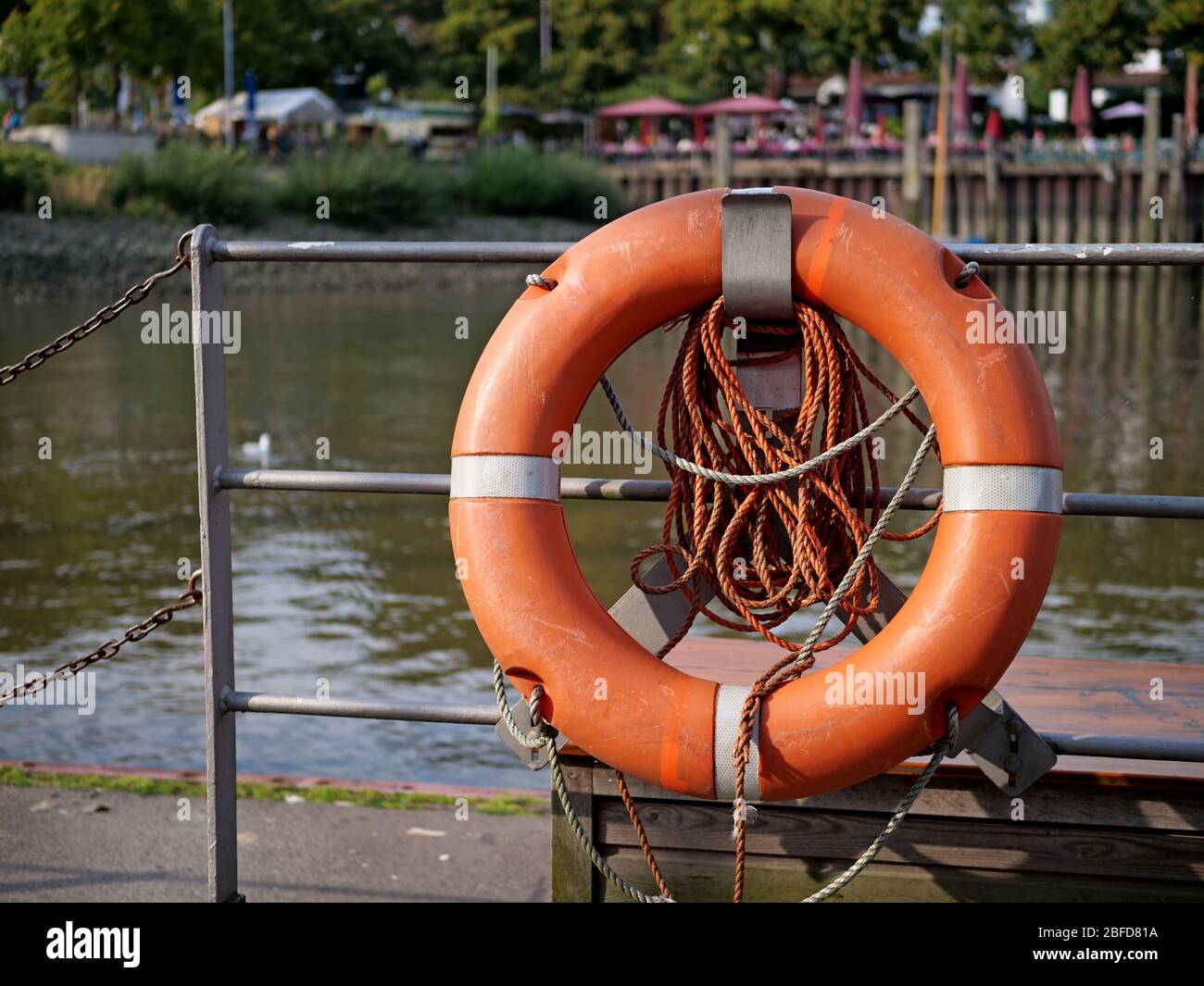 Rettungsring an der Hafenwand auf einem Metallgeländer befestigt. Stockfoto