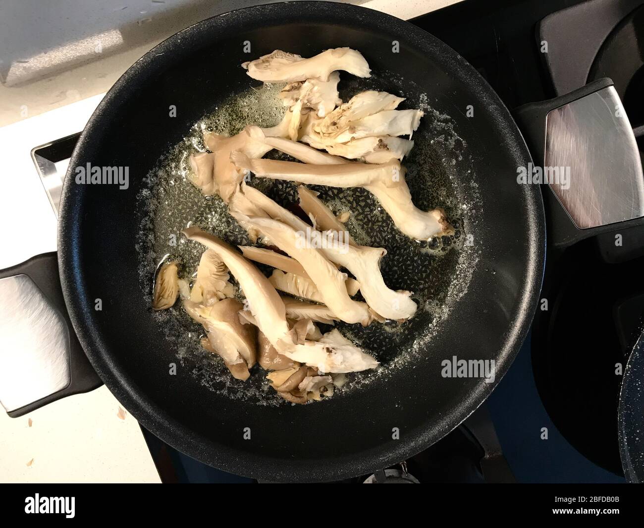 Oyster Pilze werden in Pfanne / Julienne gehackte Scheiben fritiert. Bio Gesunde Lebensmittel. Stockfoto