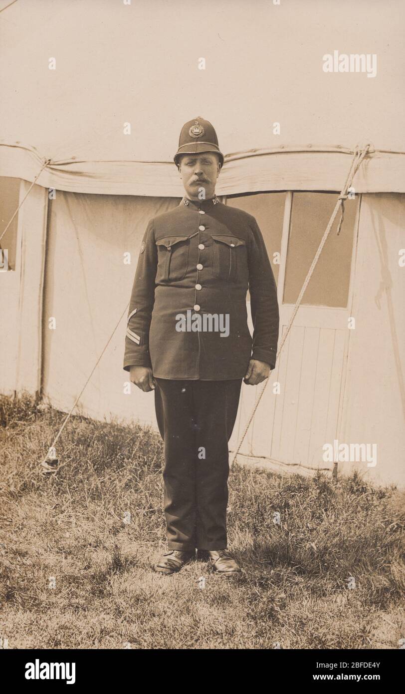 Vintage Anfang des 20. Jahrhunderts fotografische Postkarte zeigt einen britischen Polizisten posiert vor einem Zelt. Kragen Nr. D14. Stockfoto