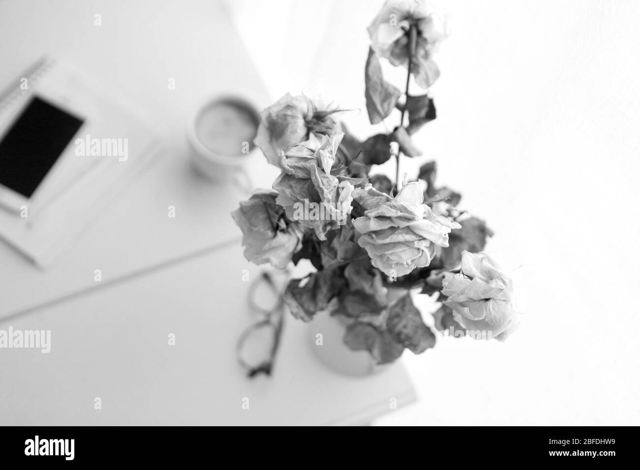 Vintage-Stil - Gläser, Notizbuch mit Bleistift und Kaffeebecher auf dem Tisch.Alte Rosen am Arbeitstisch als Zaudern oder Delay-Konzept Stockfoto