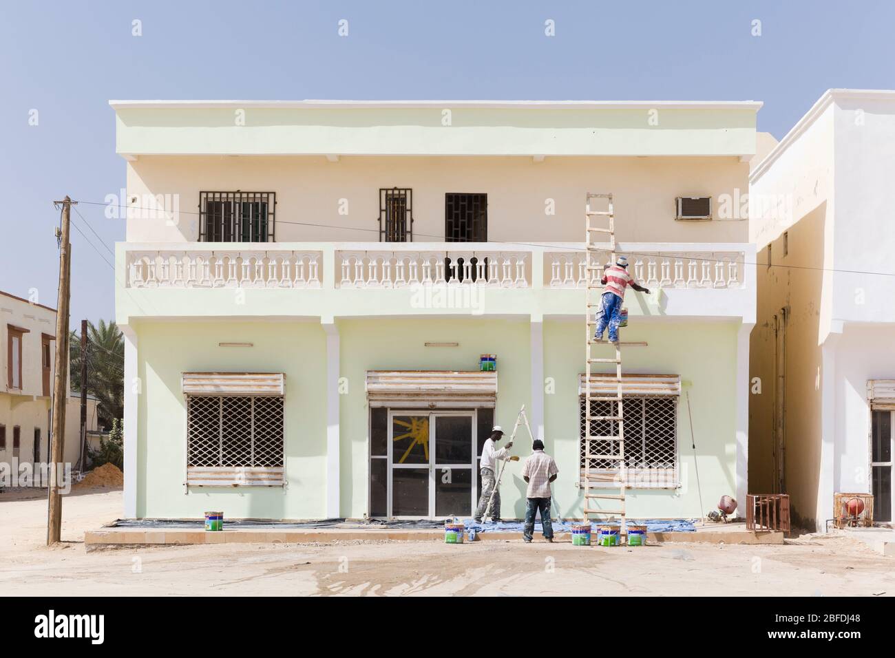 Drei Männer aus der Gegend malen ein zweistöckiges Haus in Nouakchott, Mauretanien. Stockfoto