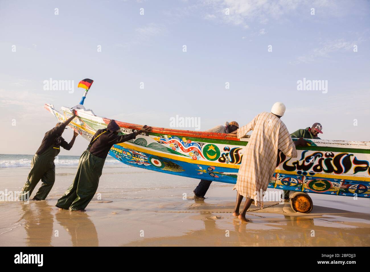 Die Crew-Mitglieder von Mohammed Sovv's Fischfang Pirogue schleppen ihr Boot nach einem Tag lang vor der Küste von Nouakchott, Mauretanien. Stockfoto