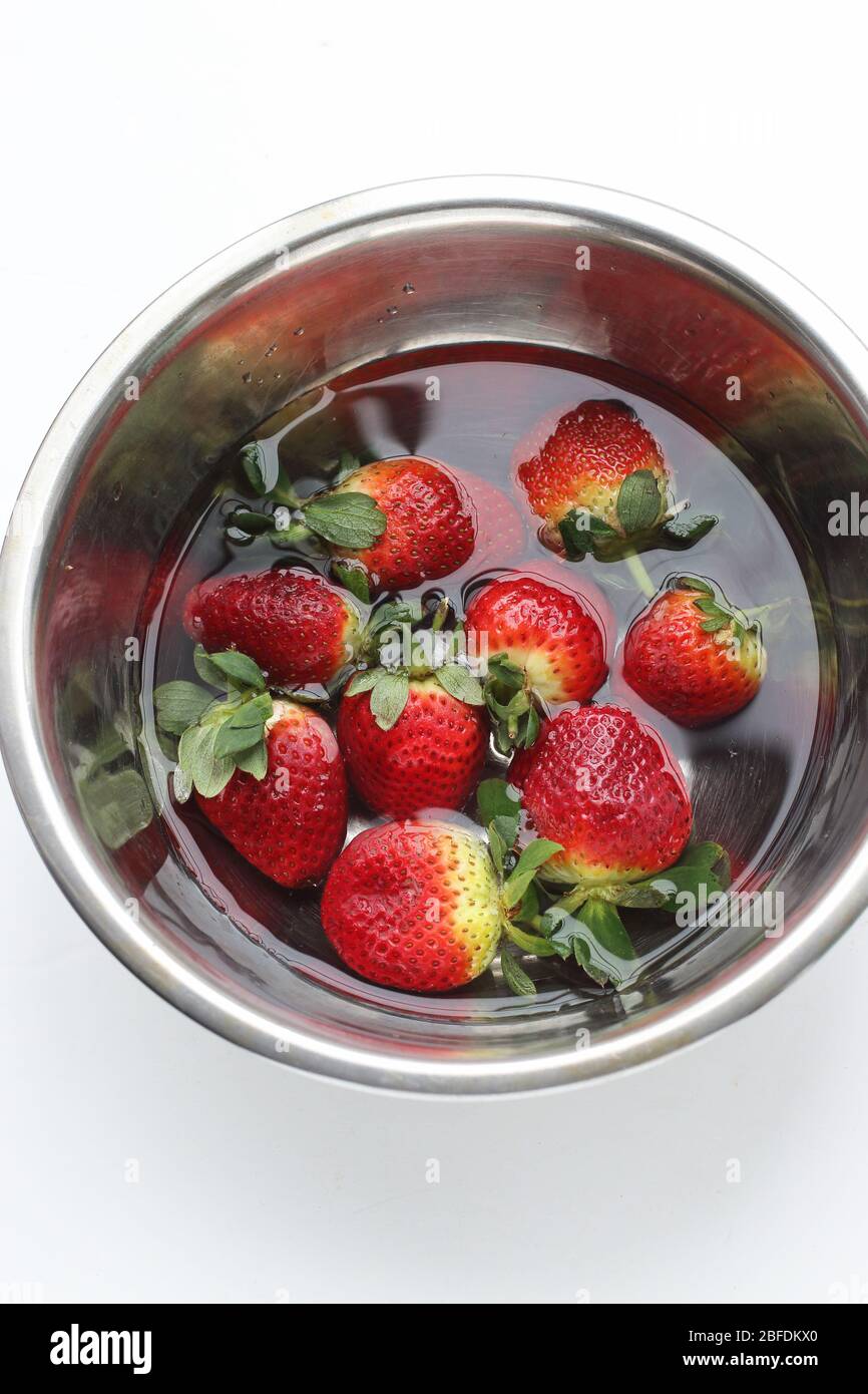 Frische Erdbeeren in Edelstahlschüssel einweichen, isoliert auf weißem Hintergrund Stockfoto