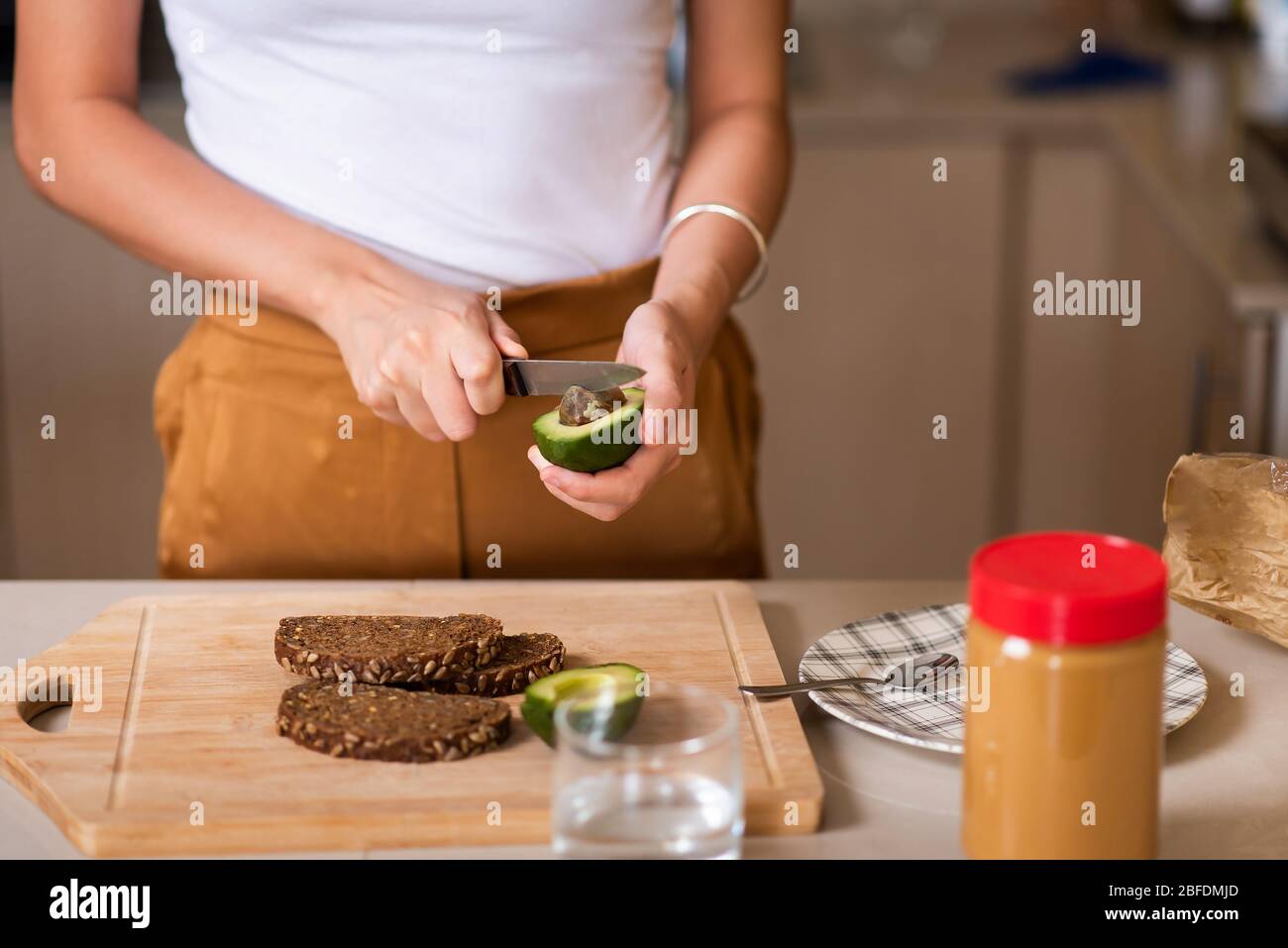 Frau macht Avocado Erdnussbutter Toast für ein gesundes Frühstück zu Hause Stockfoto Frau macht Avocado Erdnussbutter Toast für ein gesundes Frühstück zu Hause Stockfoto