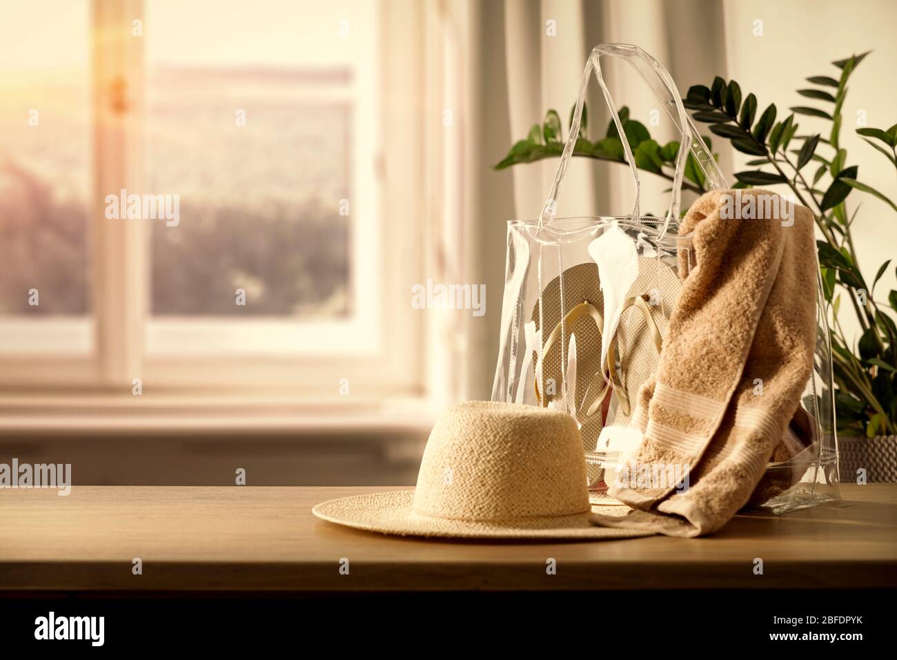 Holztisch mit Tasche und Kleidung und Kopierraum für Produkte. Schönes gemütliches und helles Zuhause. Hintergrund des Fensters mit natürlichem Licht. Stockfoto