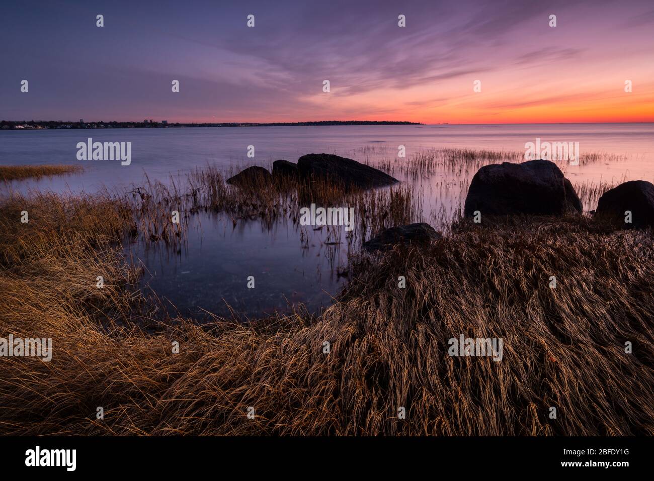 Ein Himmel in der Dämmerung leuchtet mit Farbe über dem ruhigen Wasser des Long Island Sound (Greenwich Point Park, Greenwich, Connecticut). Stockfoto