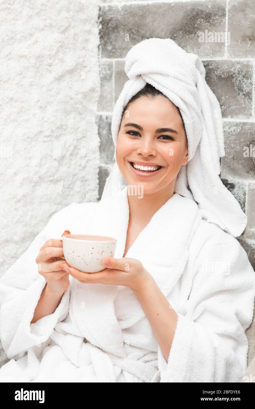 Halotherapie in einem Kurort. Schöne Frau mit Handtuch auf dem Kopf, trinkt Tee im Salzraum. Salzluftbehandlung Stockfoto