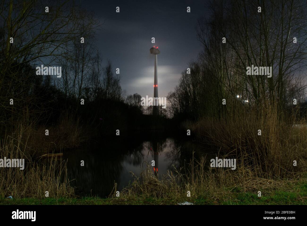 Windgeneratormotor bei Nacht Langzeitbelichtung Fotografie mit einem Teich im Vordergrund Stockfoto