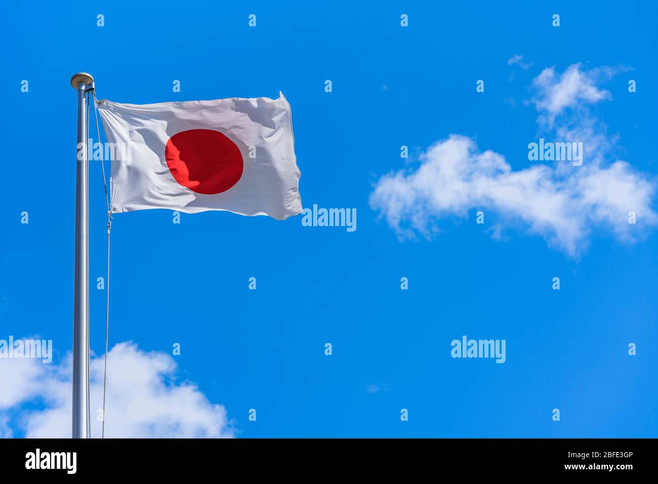 Japanische Nationalflagge, die im Wind gegen einen sonnigen blauen Himmel winkt. Stockfoto