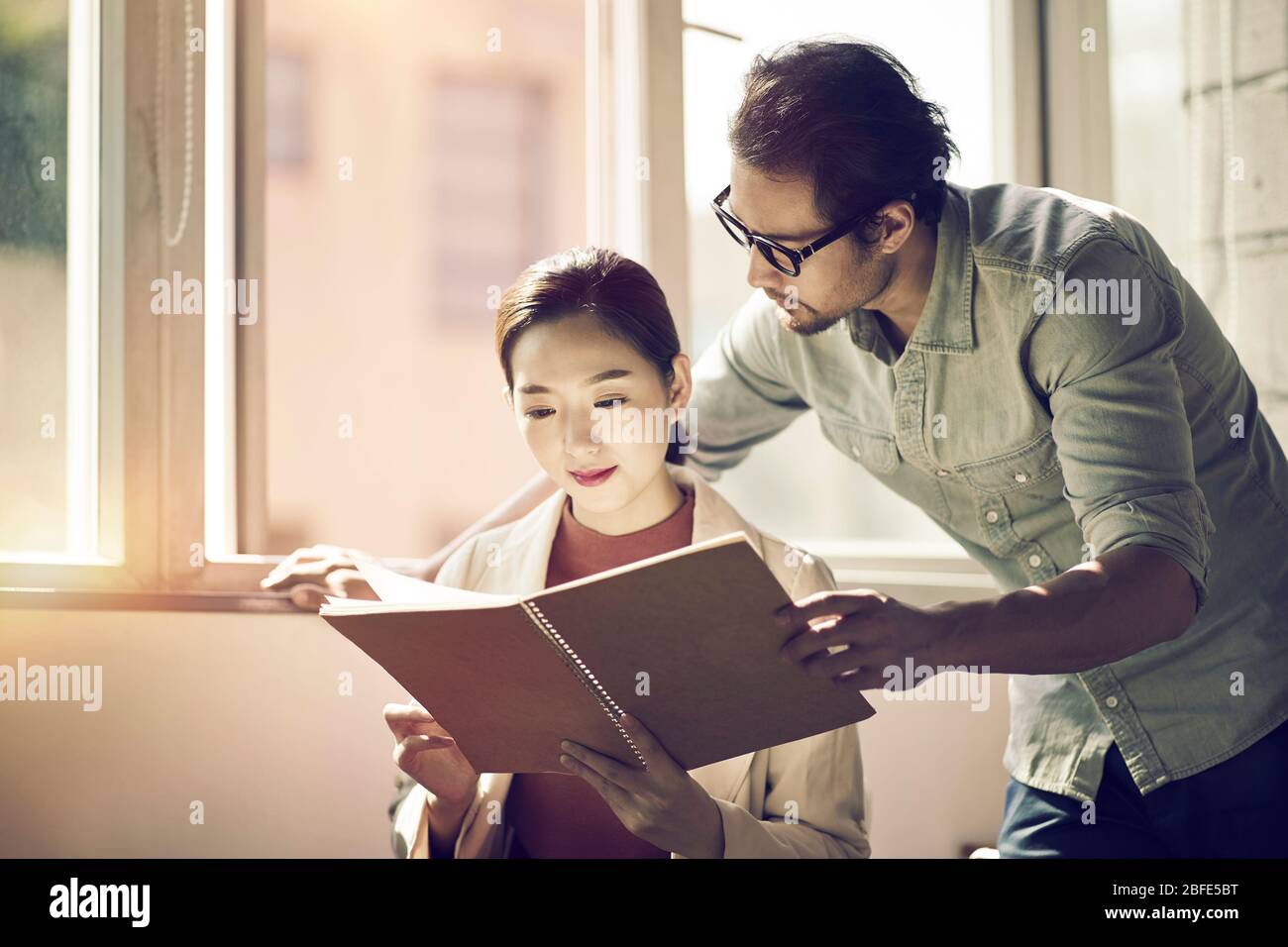 Zwei asiatische Geschäftsleute arbeiten zusammen im Büro Blick auf ein Notebook Stockfoto