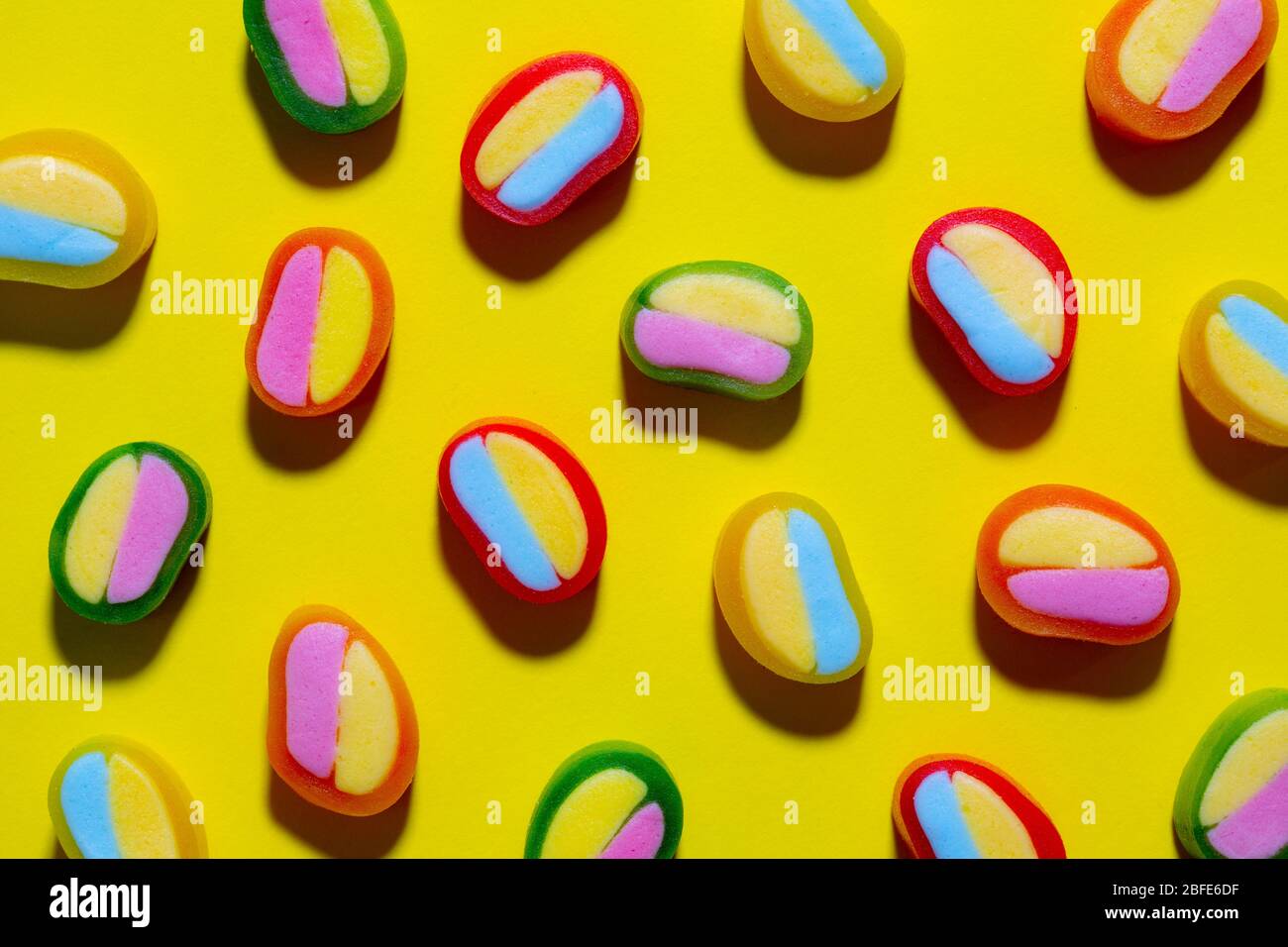 Bunte Gummibonbons, Süßigkeiten auf gelbem Hintergrund. Weiches Zahnfleisch von oben betrachtet, Tapete oder Textur, Lebensmittelkonzept Stockfoto