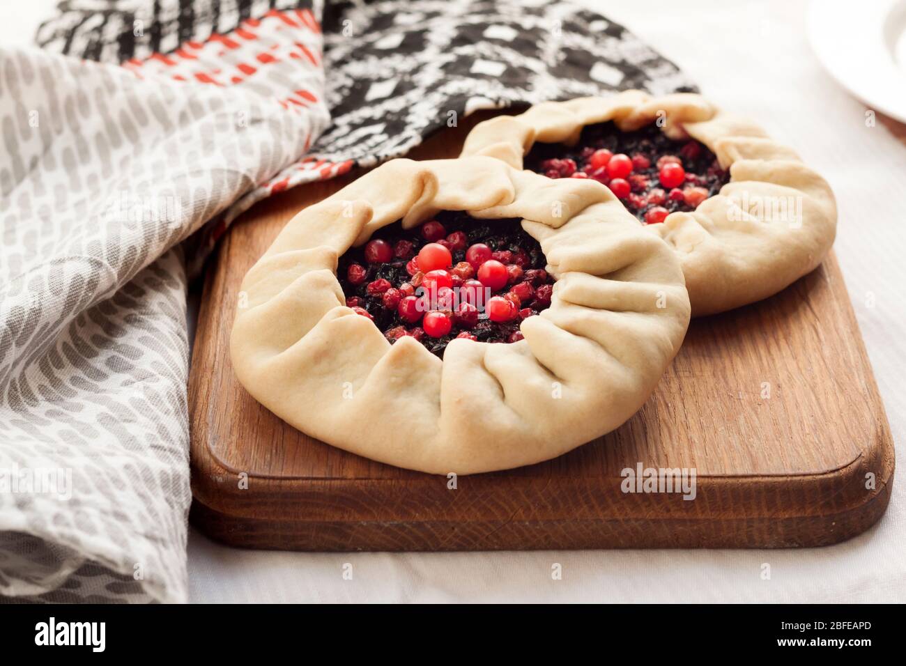 Hausgemachte süße Galette mit Holunderbeeren und Kuhbeeren auf einem Holzbrett Stockfoto