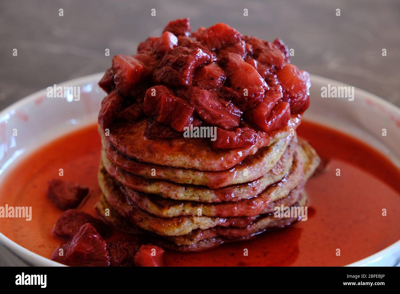 Stapel von veganen Pfannkuchen mit hausgemachter Erdbeersauce. Leckeres und gesundes hausgemachtes Frühstück. Stockfoto