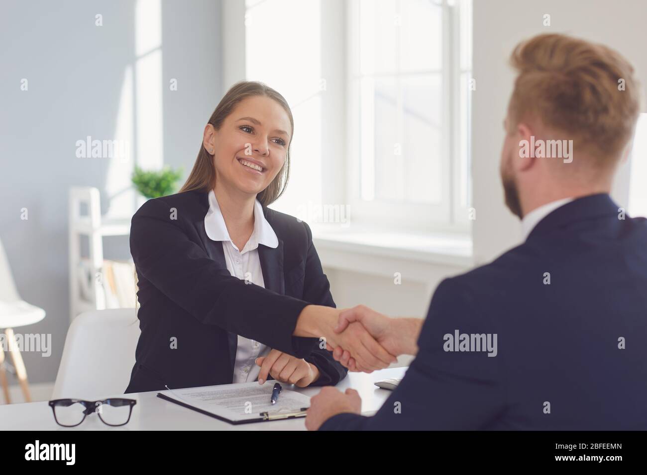 Erfolgreiches Bürointerview. Der Vertragsabschluss. Unternehmer und Geschäftsfrau händerinschen nach dem Treffen am Tisch. Stockfoto