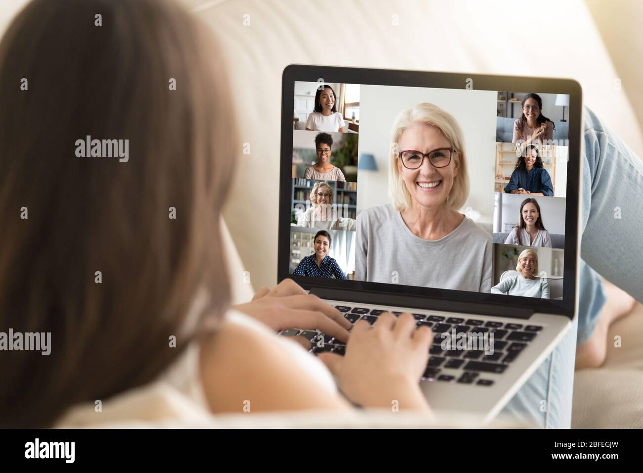 Mädchen verwenden Laptop beteiligt an Gruppe Videocall mit verschiedenen Frauen Stockfoto