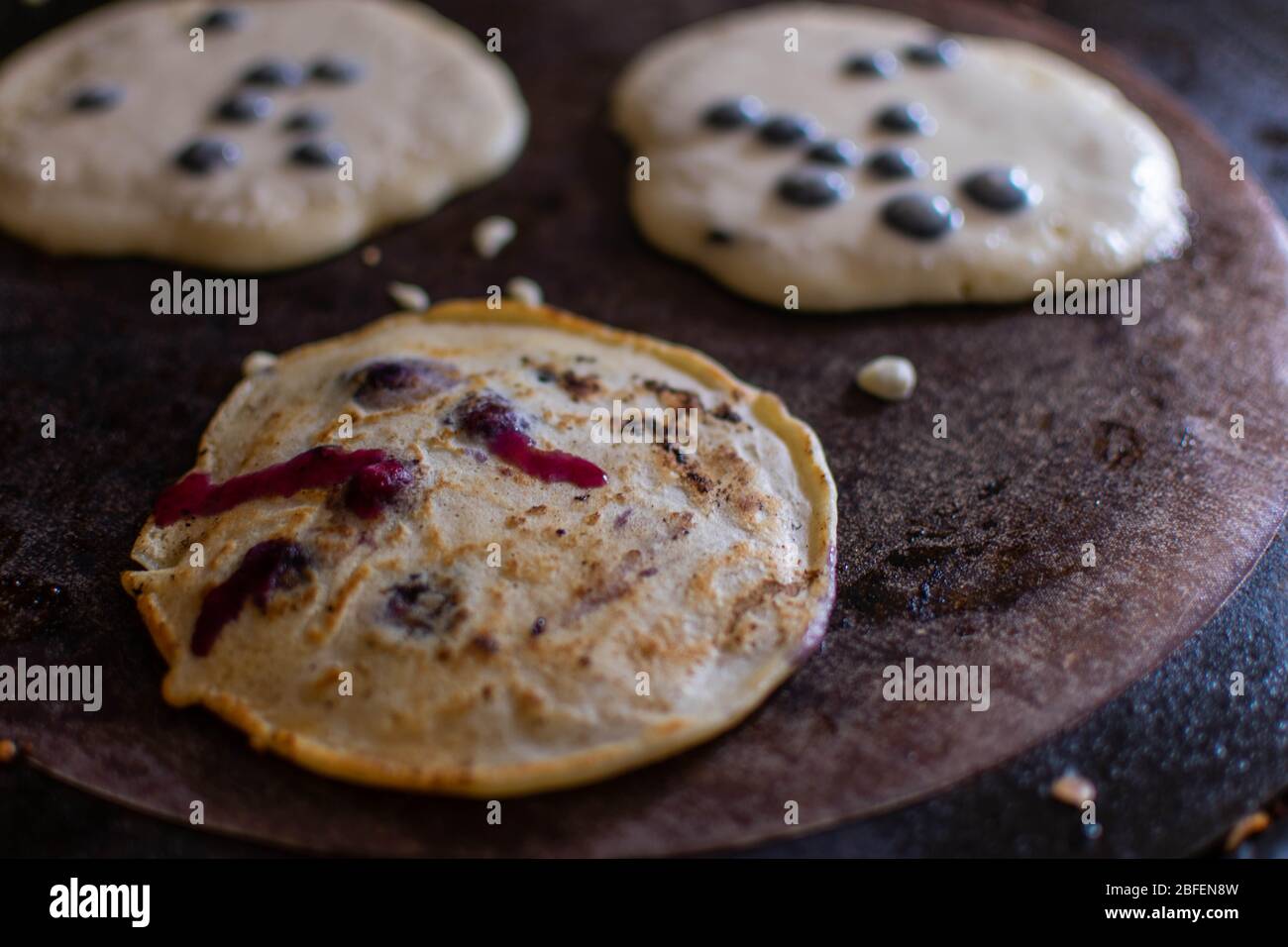 Nahaufnahme von drei Heidelbeer-Pfannkuchen, die auf einem AGA-Kochplatte zubereitet werden Stockfoto