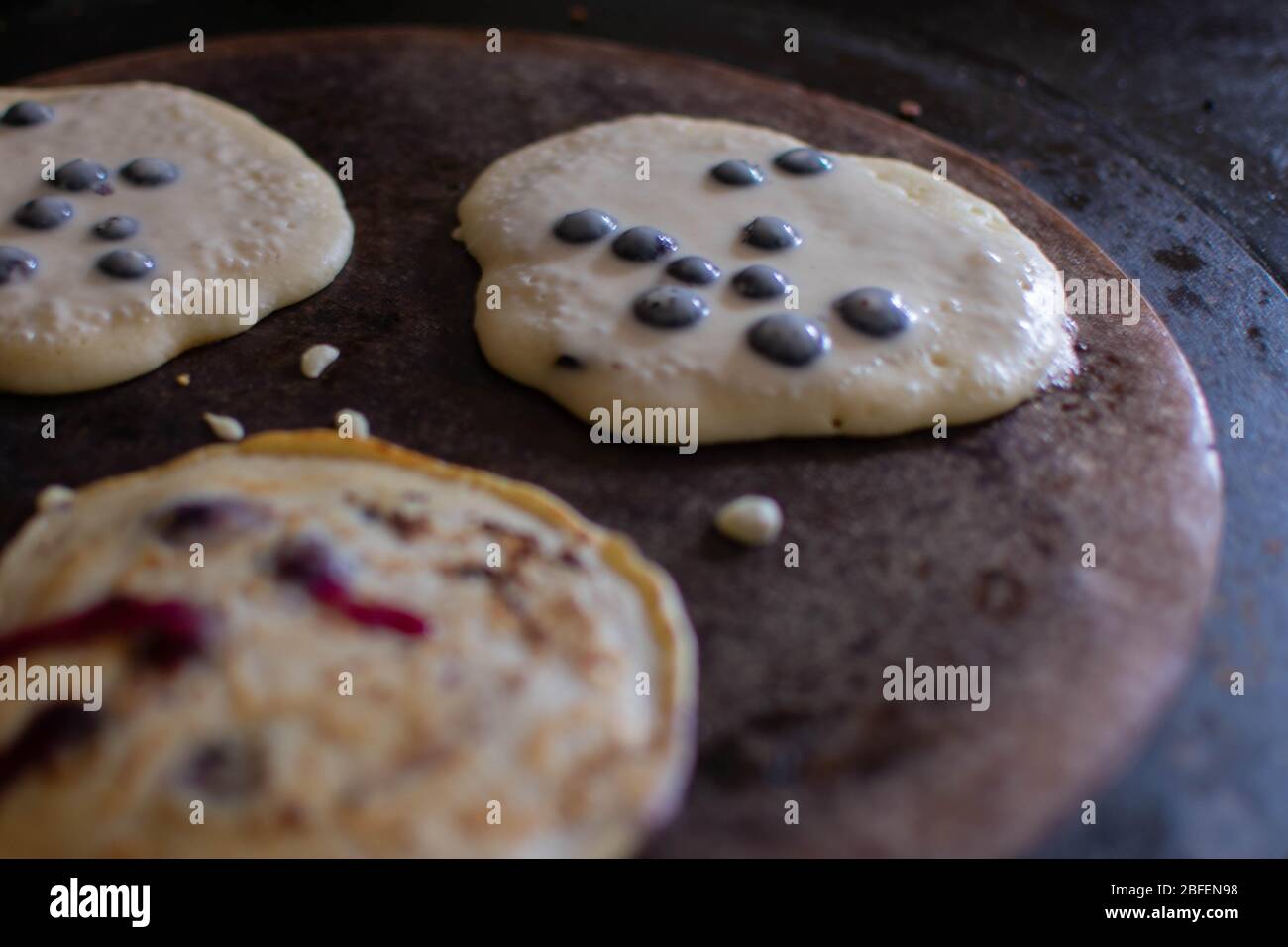 Drei leckere frische Heidelbeer-Pfannkuchen, die auf dem Kochplatte eines traditionellen AGA-Kochers zubereitet werden Stockfoto
