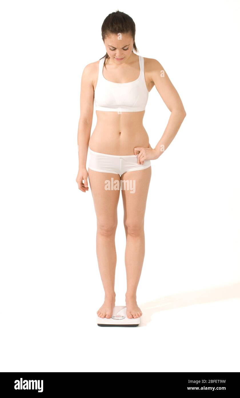 Eine junge Frau, die sich auf einer Badezimmerwaage wiegt -Model veröffentlicht Stockfoto