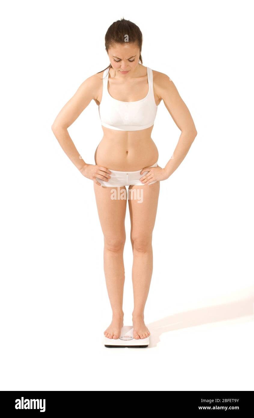 Eine junge Frau, die sich auf einer Badezimmerwaage wiegt -Model veröffentlicht Stockfoto