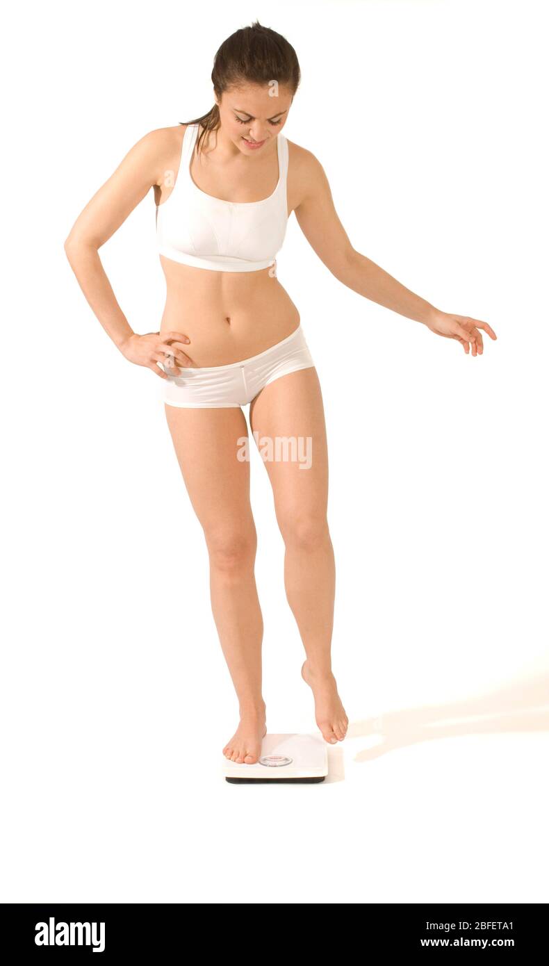 Eine junge Frau, die sich auf einer Badezimmerwaage wiegt -Model veröffentlicht Stockfoto