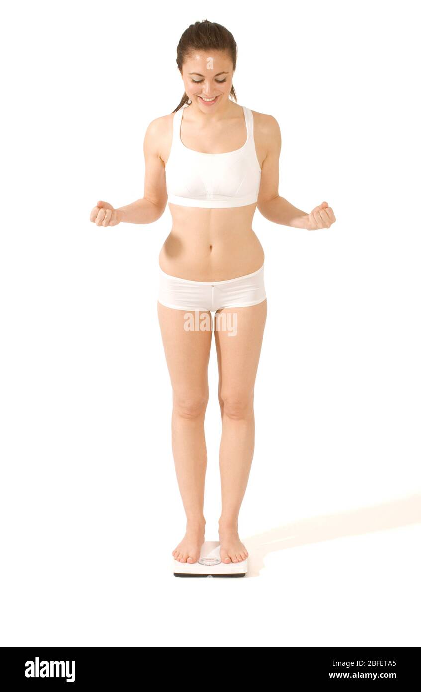 Eine junge Frau, die sich auf einer Badezimmerwaage wiegt -Model veröffentlicht Stockfoto