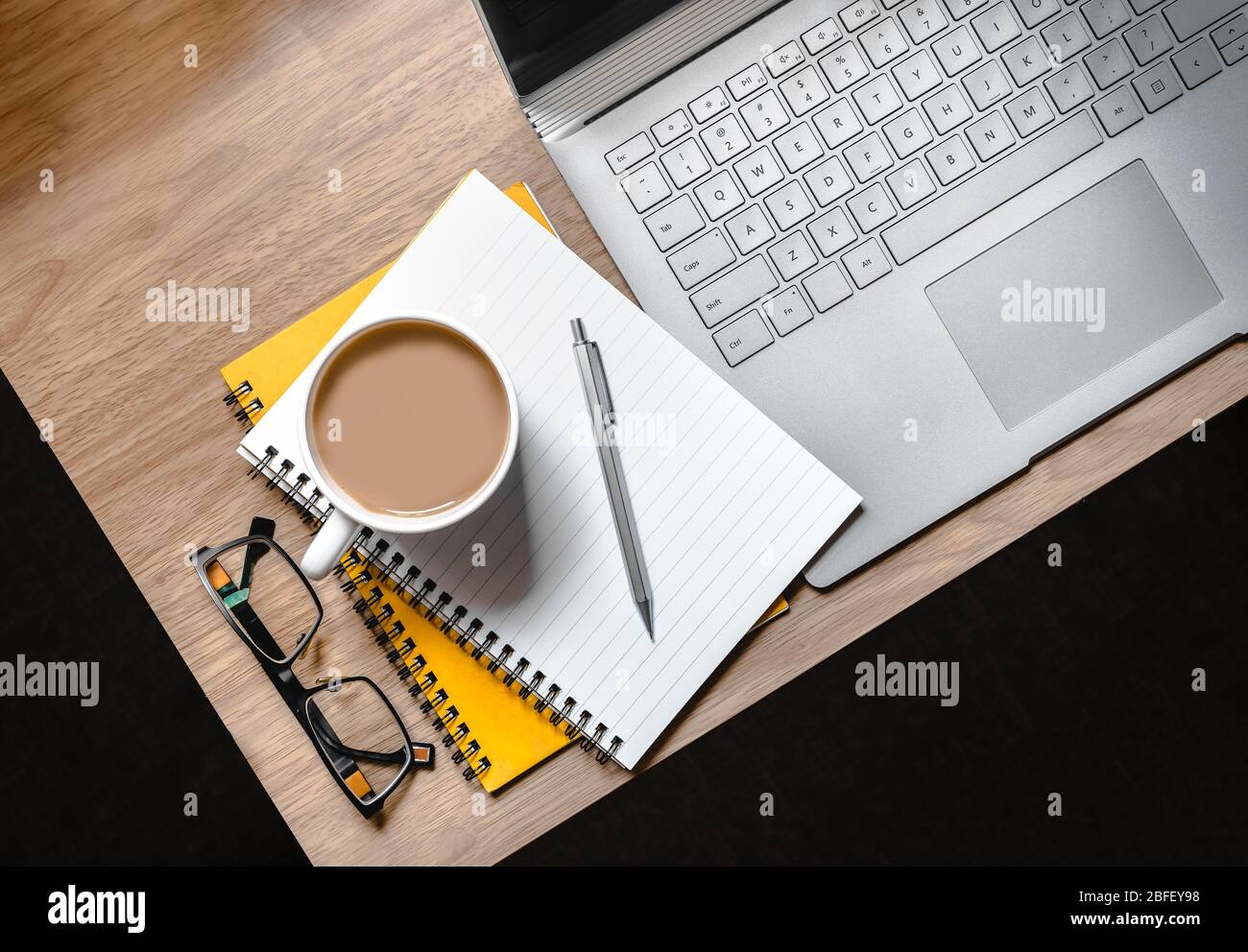 WFH - Work from Home Flatlay Foto vom Schreibtisch mit Laptop, Notizblock, Brille und Tasse Tee Stockfoto