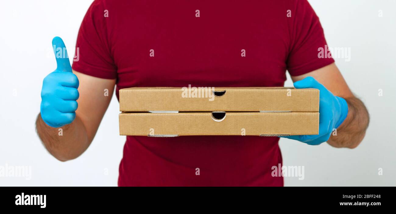 Pizzalieferung während der Quarantäne. Ein Kurier in medizinischen Handschuhen hält Pizzakisten. Kontaktlose Lieferung Stockfoto