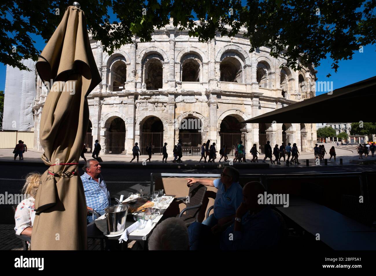 Menschen sitzen auf Café-Esplanade vor der Arena von Nîmes römischen Amphitheater in Nimes, Frankreich, Europa Stockfoto